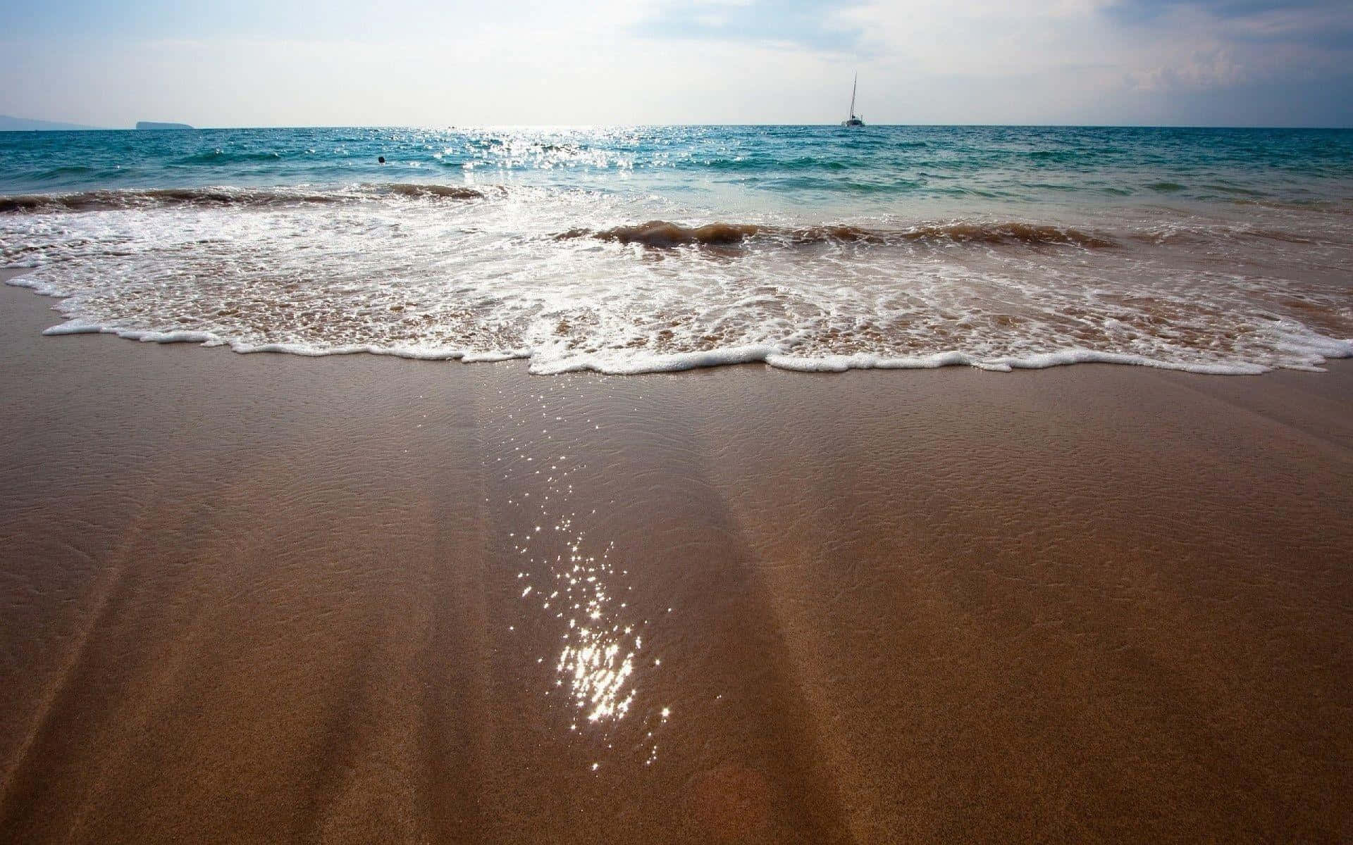 海浪沖刷濕沙，地平線上可見一艘帆船。