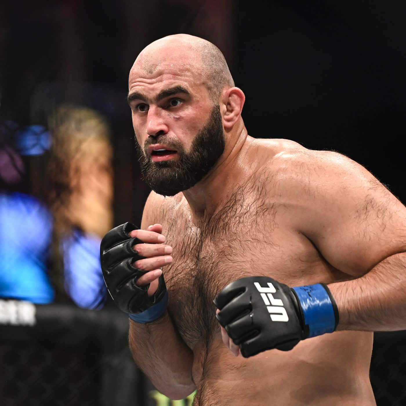 光頭鬍鬚的MMA拳手戴著UFC手套，在比賽中擺出戰鬥姿勢。