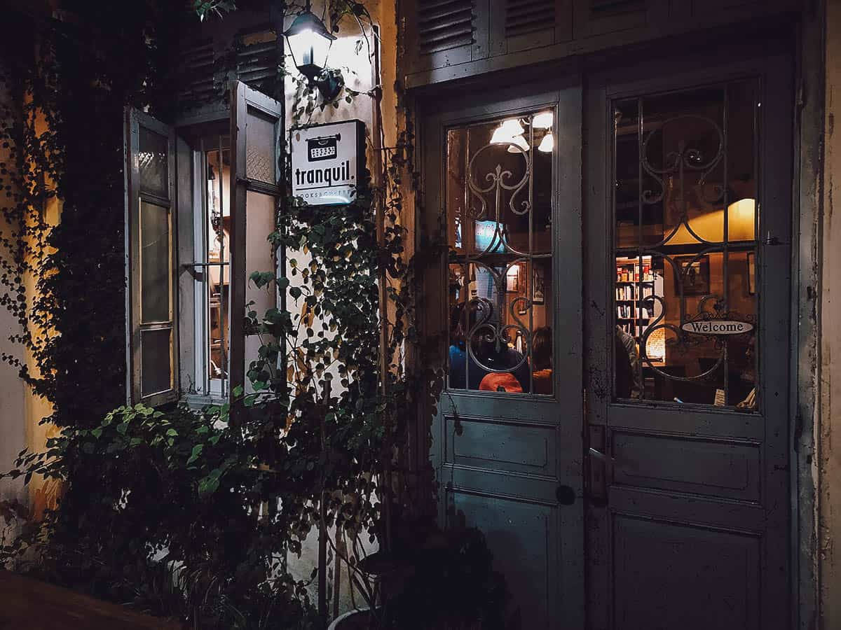 河內古董店風情 壁紙 — 夜晚一間舒適的復古咖啡店入口，常春藤攀爬牆壁，溫暖的室內燈光透過華麗的玻璃門閃爍。