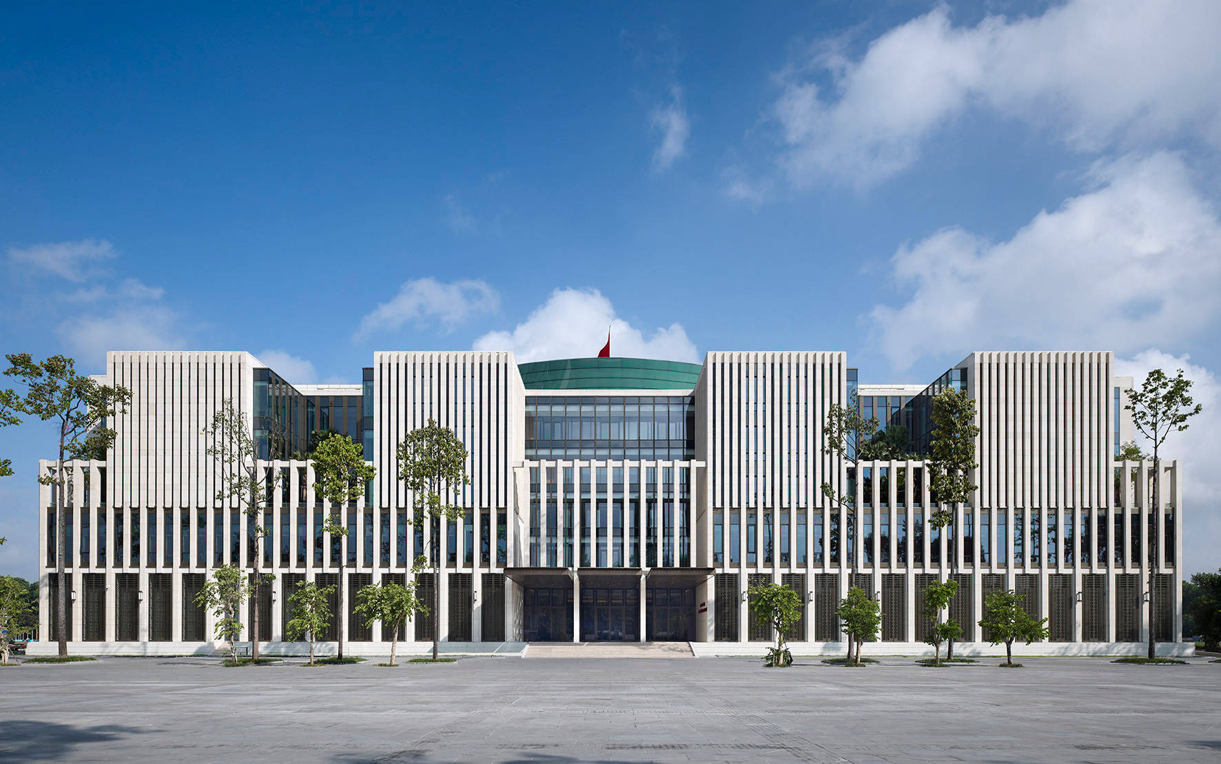 河內巴亭廣場壯麗景觀 壁紙 — 現代白色建築，帶有垂直條紋和玻璃幕牆，在明亮的藍天下有零星雲朵。