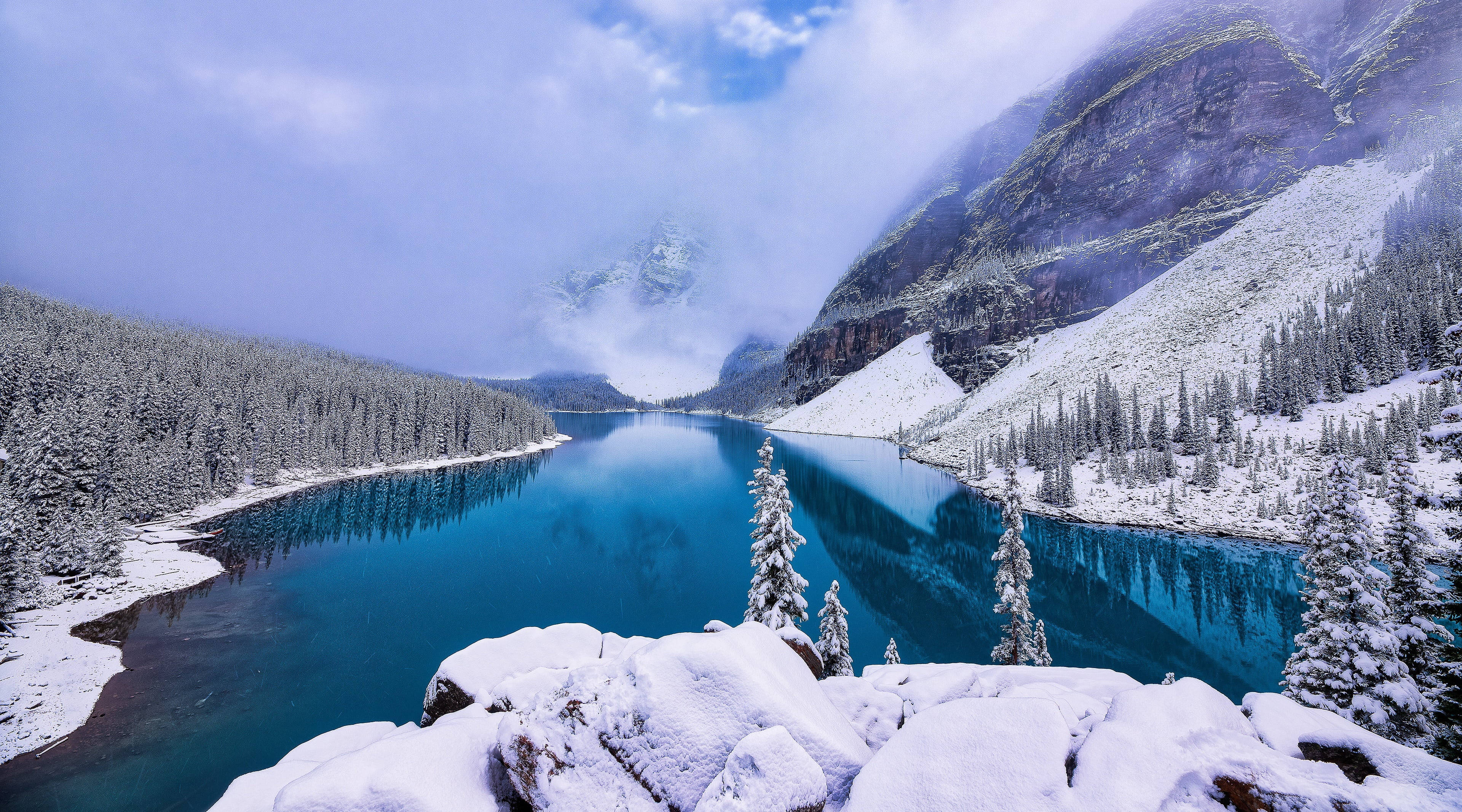 河山霧氣冬日晨景 壁紙 — 一個被雪覆蓋的山湖映照出充滿活力的藍天和霧氣繚繞的山峰，周圍環繞著常綠森林。