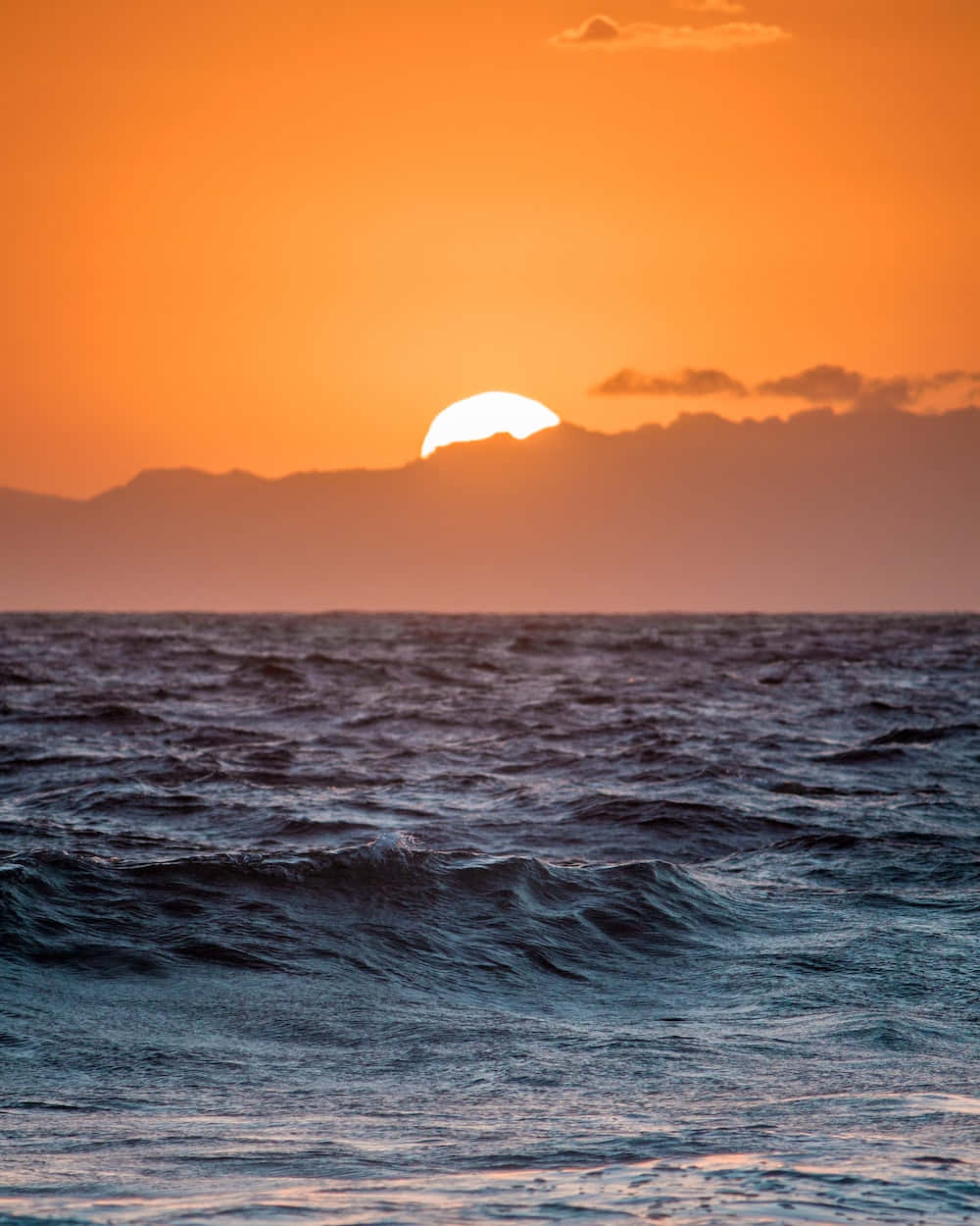 海洋上的夕陽，遠方有山