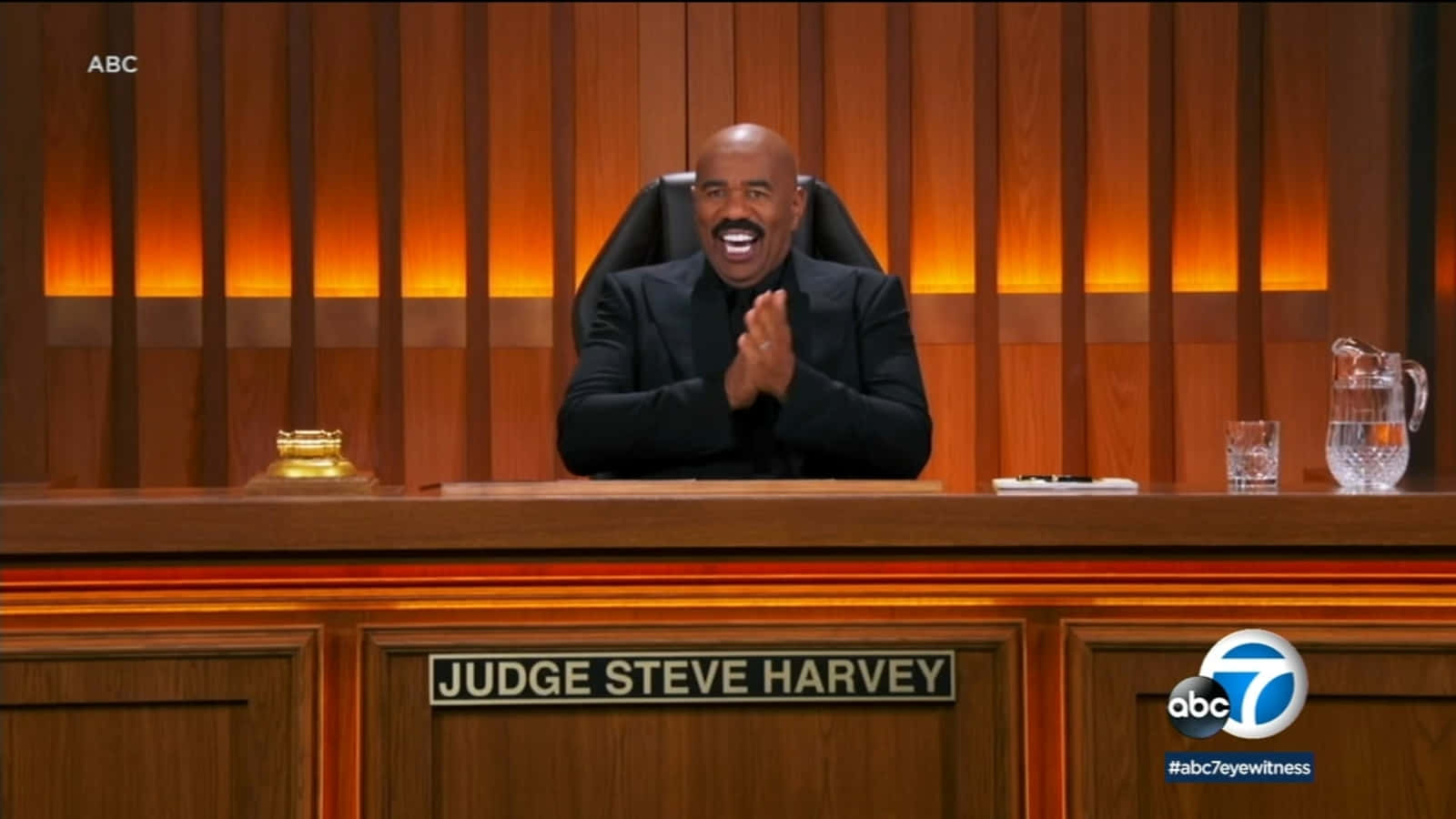 法官Steve Harvey在法庭桌後拍手微笑。