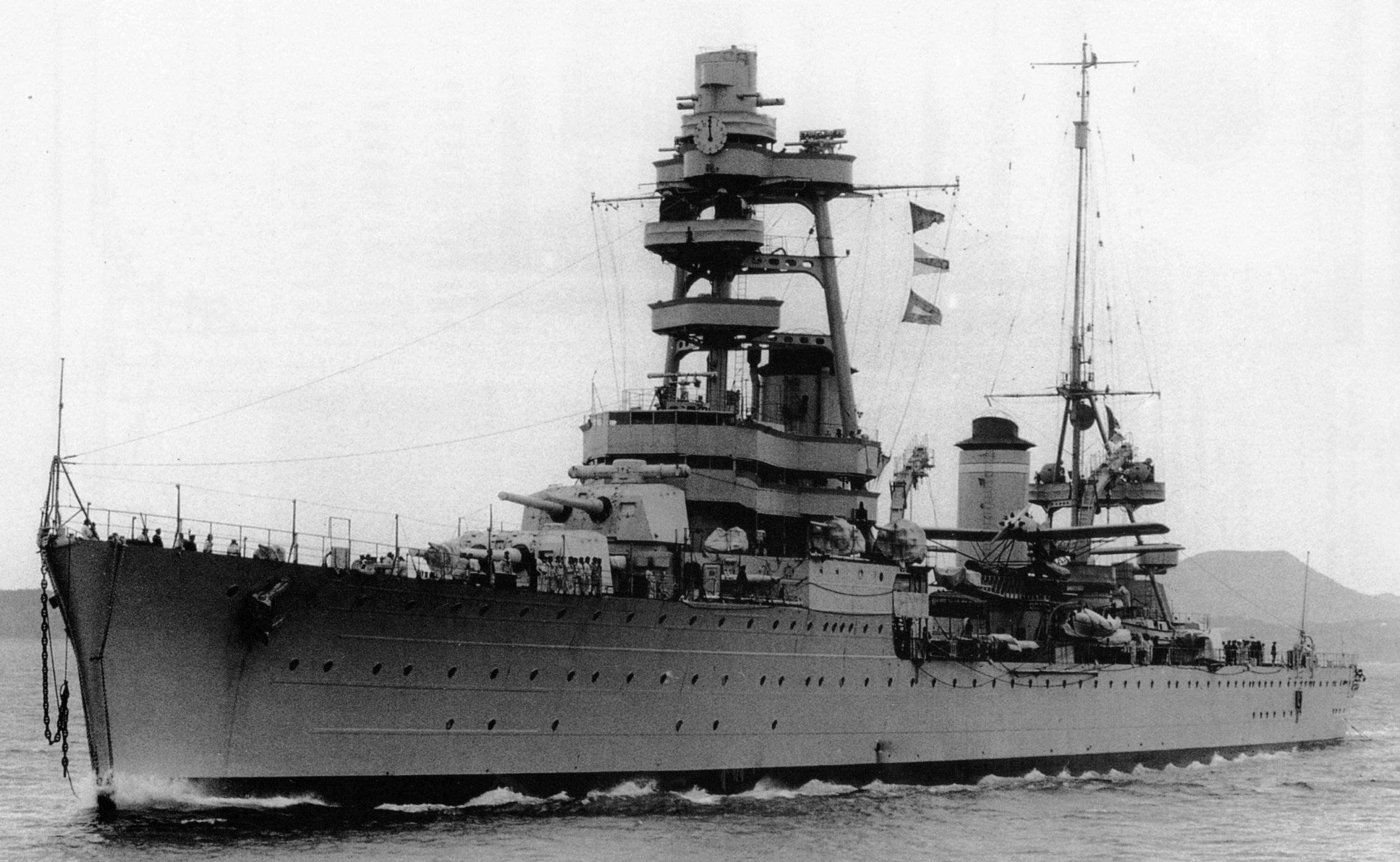 法屬波利尼西亞海軍艦艇 壁紙 — 一艘巨大的戰艦在平靜的水面上航行，甲板上可見船員，背景有山丘。