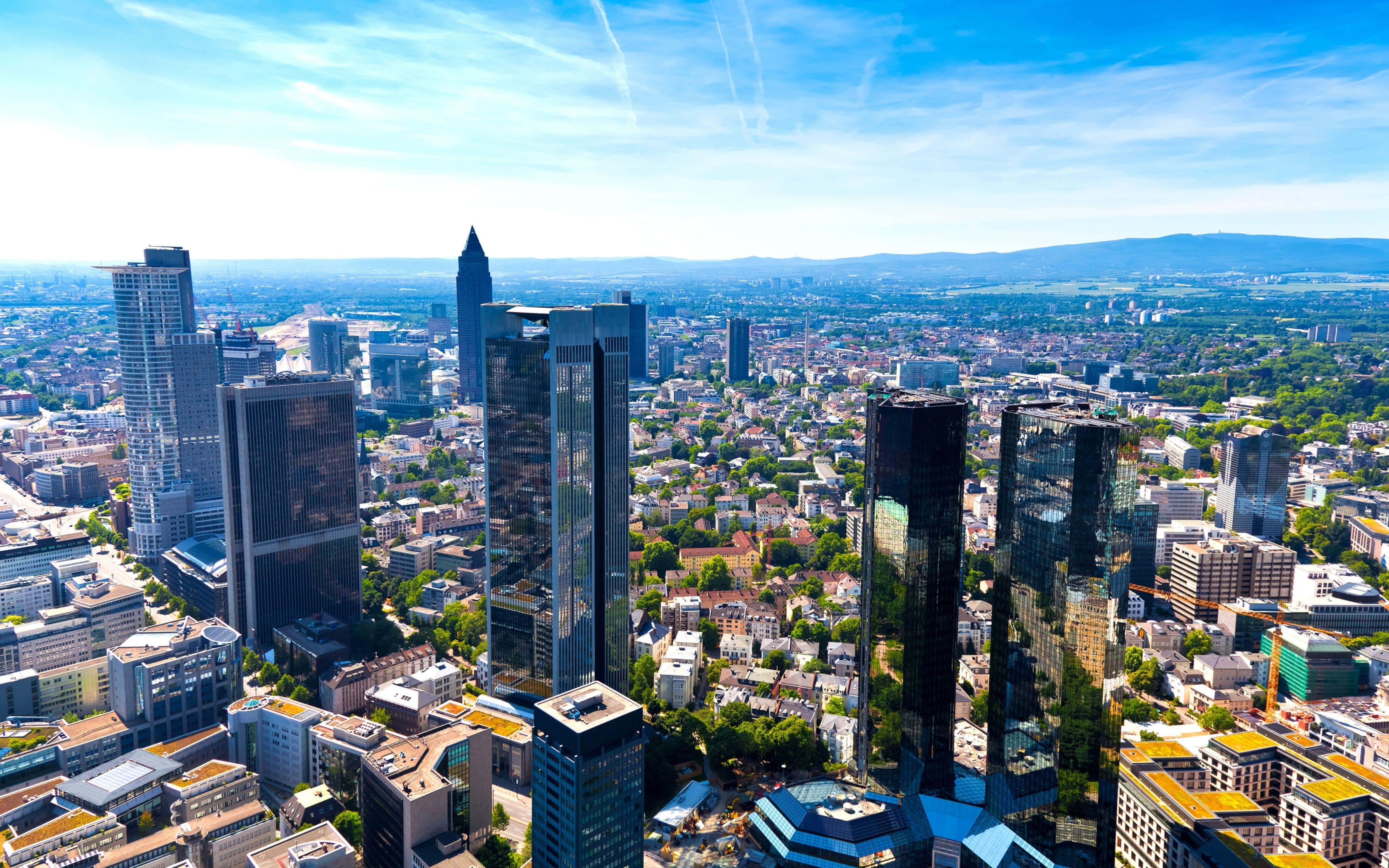 Germany 桌布 壁紙 — 法蘭克福天際線的鳥瞰圖，玻璃摩天大樓和歷史建築在明亮的藍天白雲下。