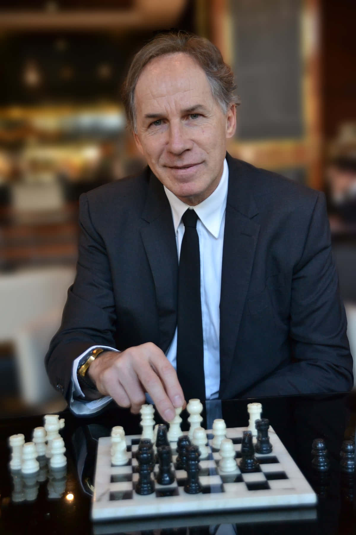 穿西裝的男子在室內專注地下棋。
