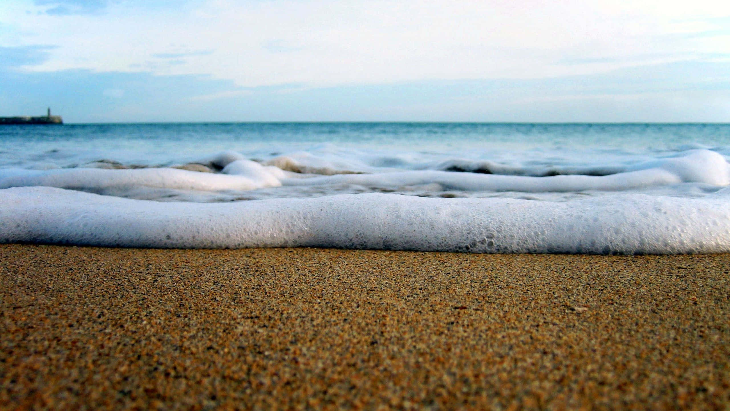 海浪 桌布 壁紙 — 泡沫海浪輕輕拍打著質感豐富的金色沙灘，天空柔和湛藍。