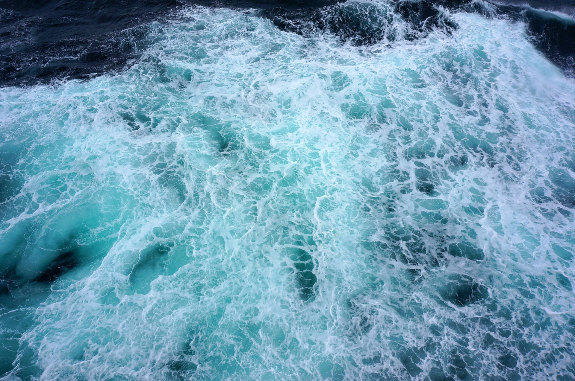 船尾波浪中翻騰的泡沫狀藍綠色海水