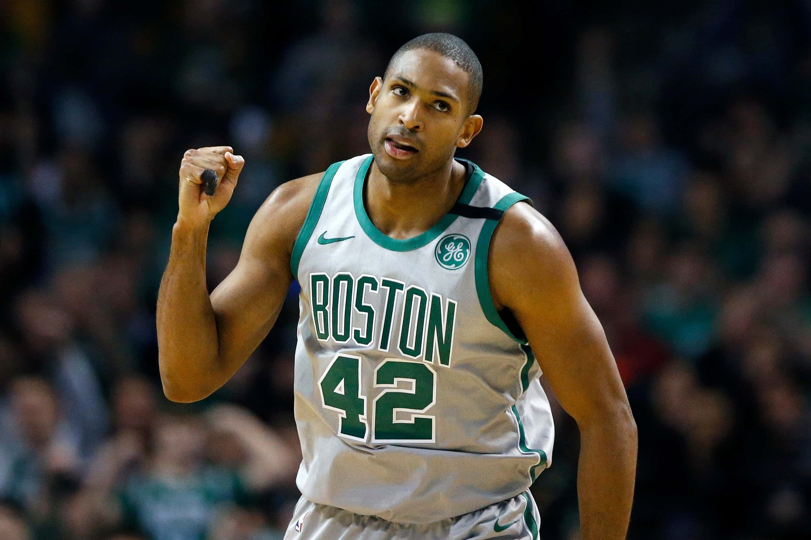 Al Horford 桌布 壁紙 — 波士頓塞爾特人隊42號球員在場館燈光下的一場籃球比賽中握拳慶祝。