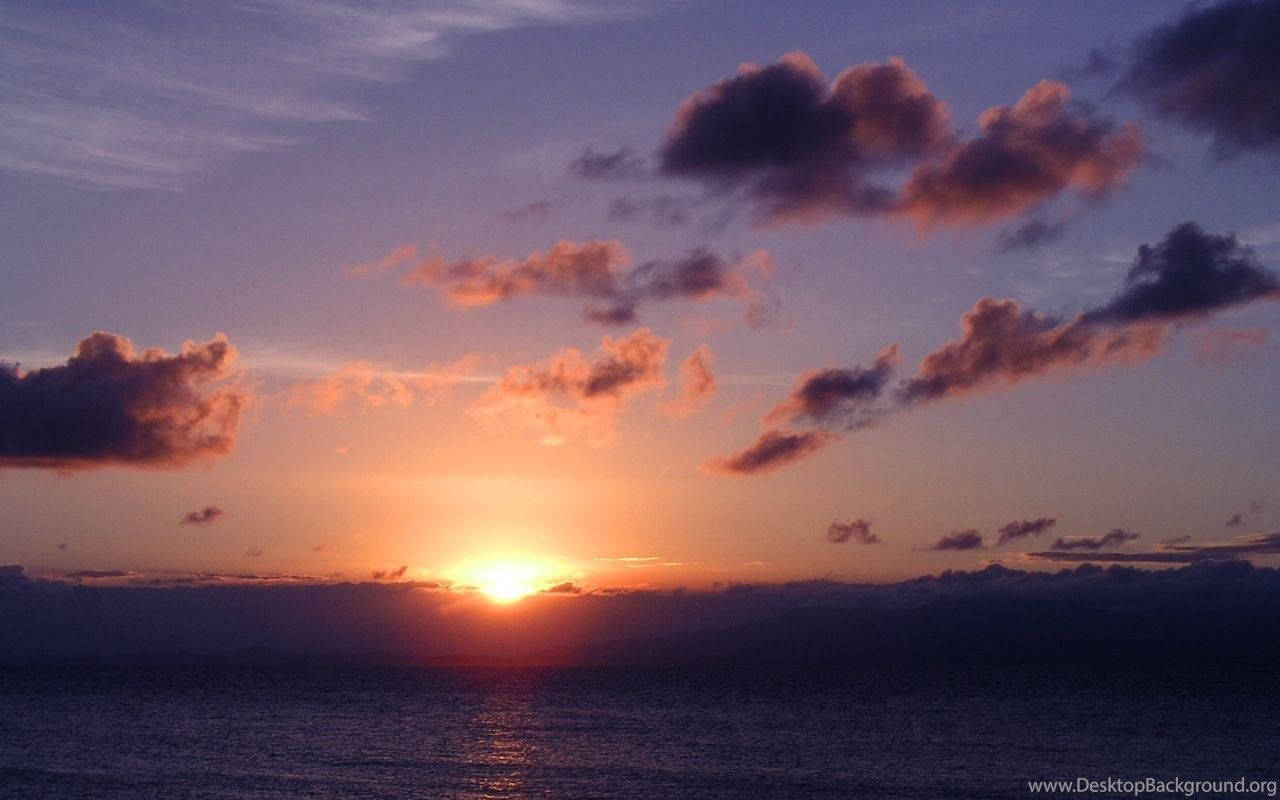 夕陽映照海洋，彩色雲朵反射金色光芒。