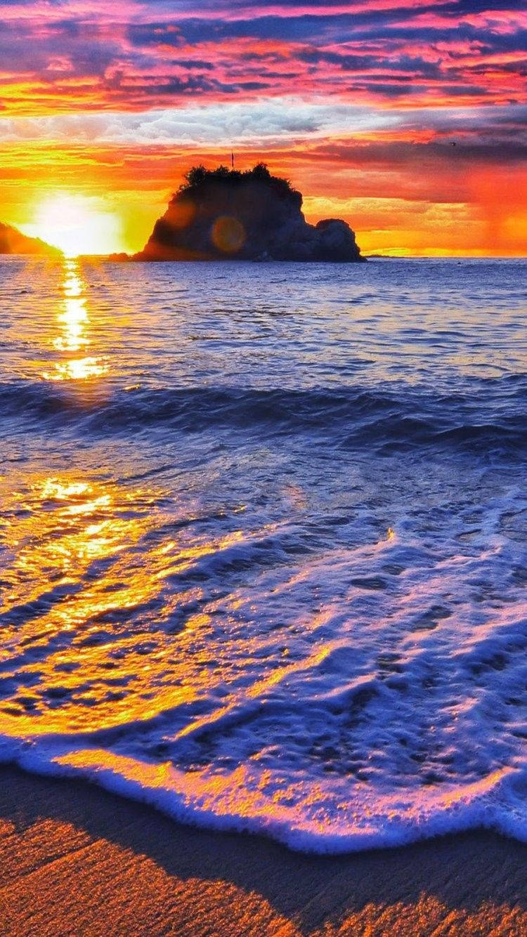 海洋上的夕陽，海浪拍打沙灘，岩石島輪廓