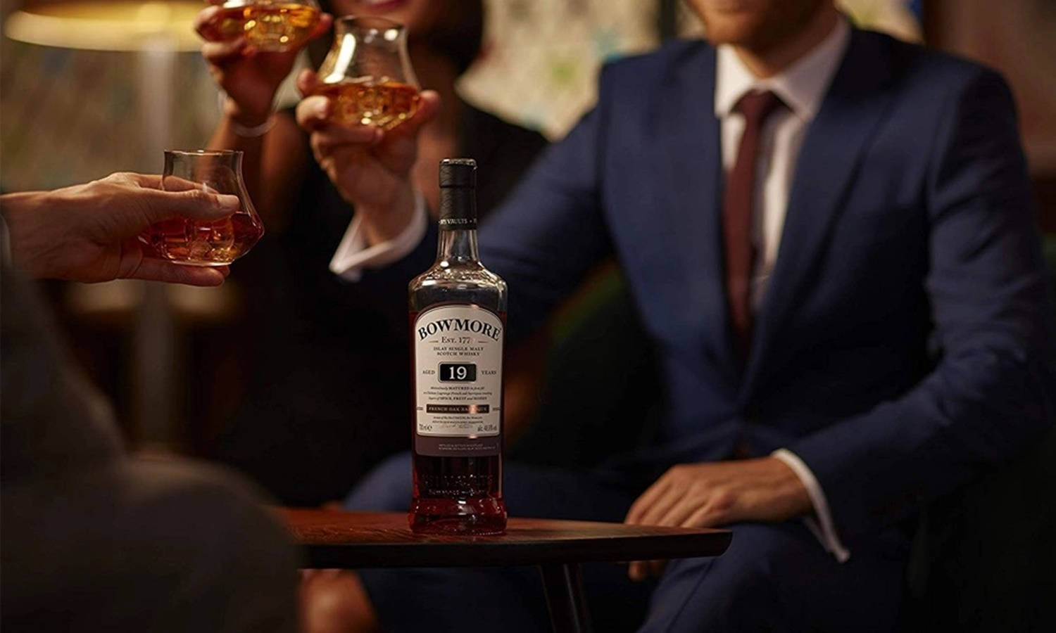 人們圍著一瓶Bowmore 19年威士忌舉杯祝酒。