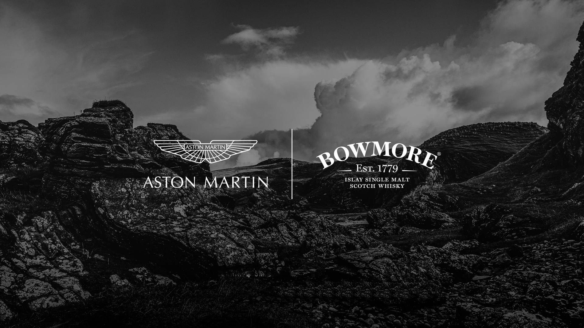 Aston Martin 和 Bowmore 標誌顯示在多岩石的山景上。