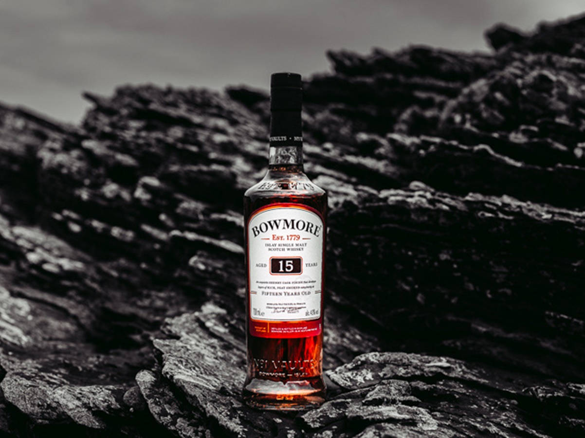 一瓶Bowmore 15年威士忌放在深色海岸岩石上。