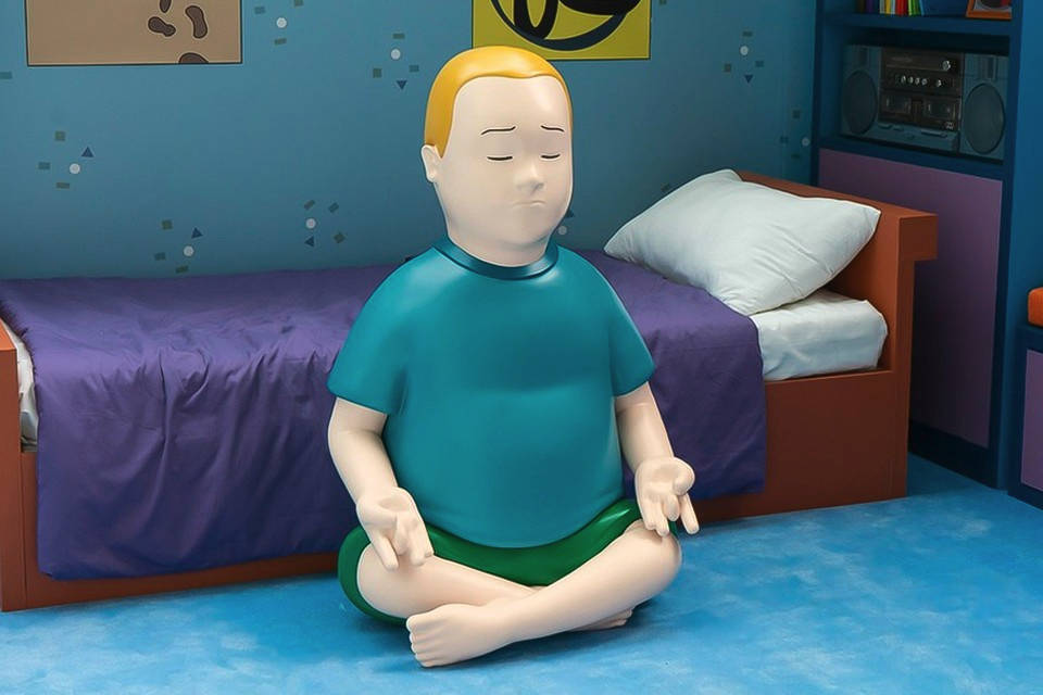 波比·希爾 3D 藝術 壁紙 — 一個大型風格化的男孩蓮花坐姿雕像，在一個有紫色床單和藍色牆壁的兒童房中平靜地冥想。