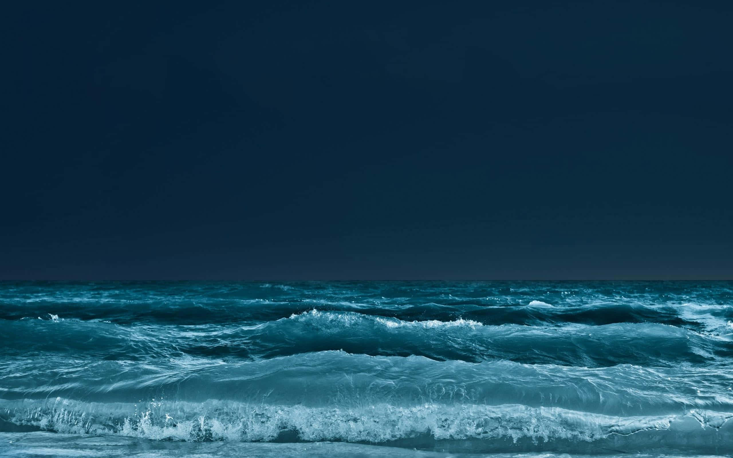 Dark Ocean 桌布 壁紙 — 波濤洶湧的海洋，深藍色的波浪在黑暗陰沉的天空下翻騰。