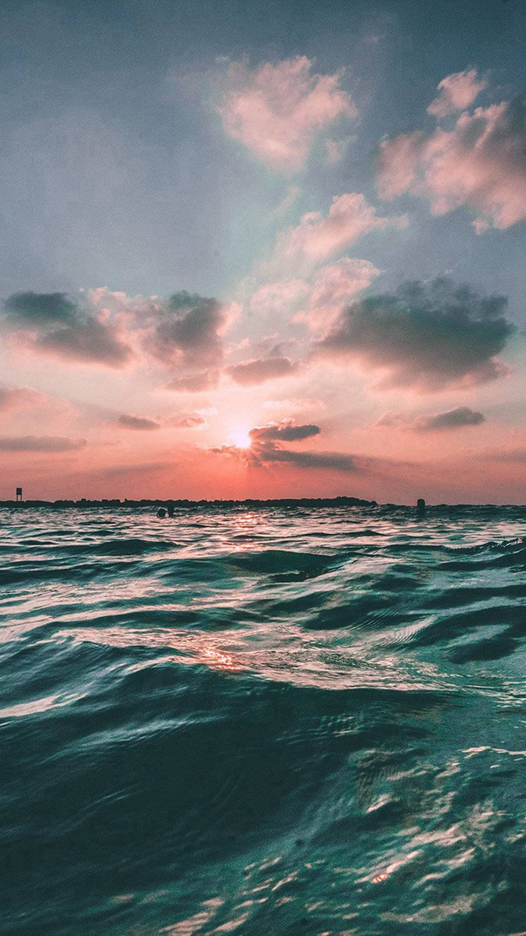 夕陽映照海洋，粉橙色天空，波光粼粼