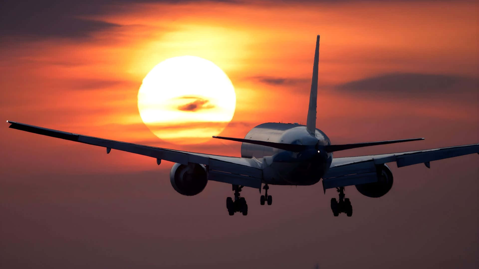 波音 737 夕陽降落 壁紙 — 一架商用飛機在鮮豔的橙色日落中剪影，太陽正好在其後方。
