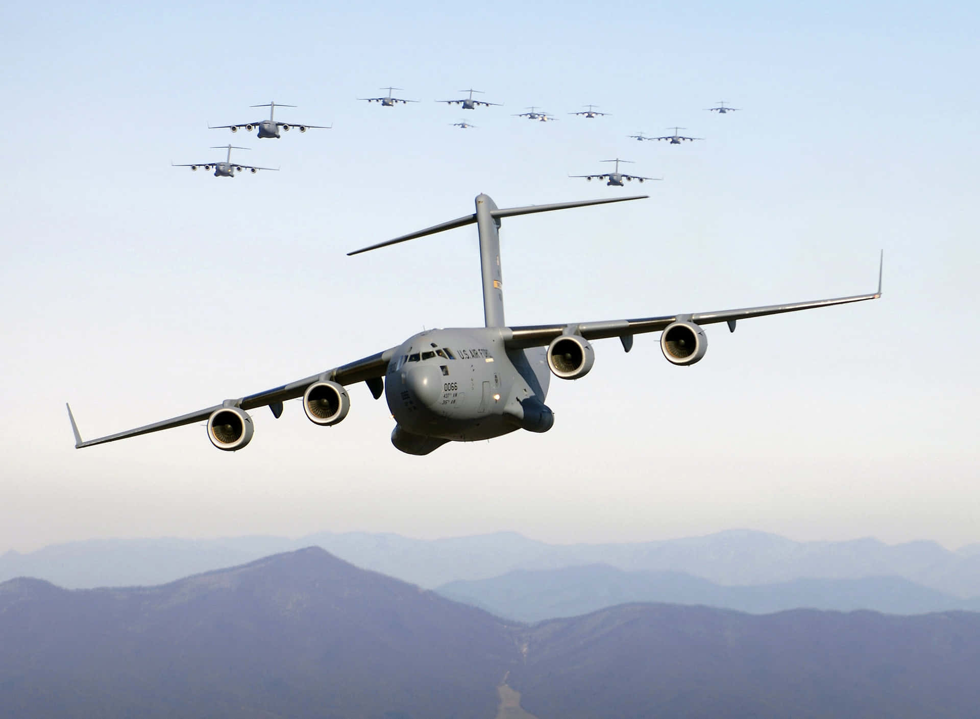 軍用運輸機在山脈上空編隊飛行