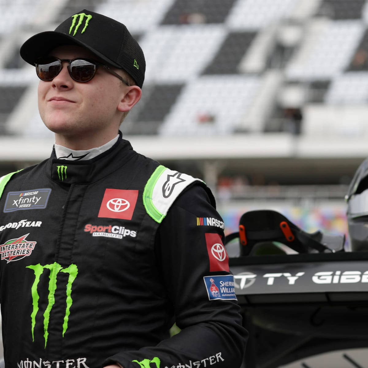 NASCAR車手身穿賽車裝備站在體育館的賽車旁