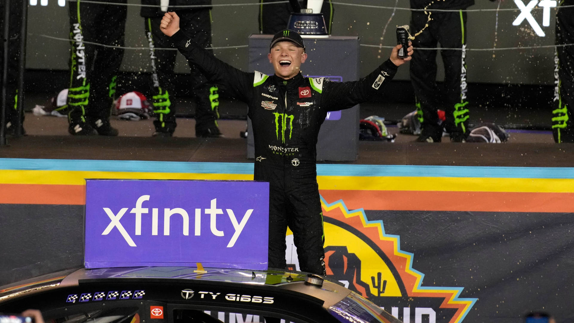 NASCAR車手在賽車引擎蓋上高舉雙臂慶祝勝利。