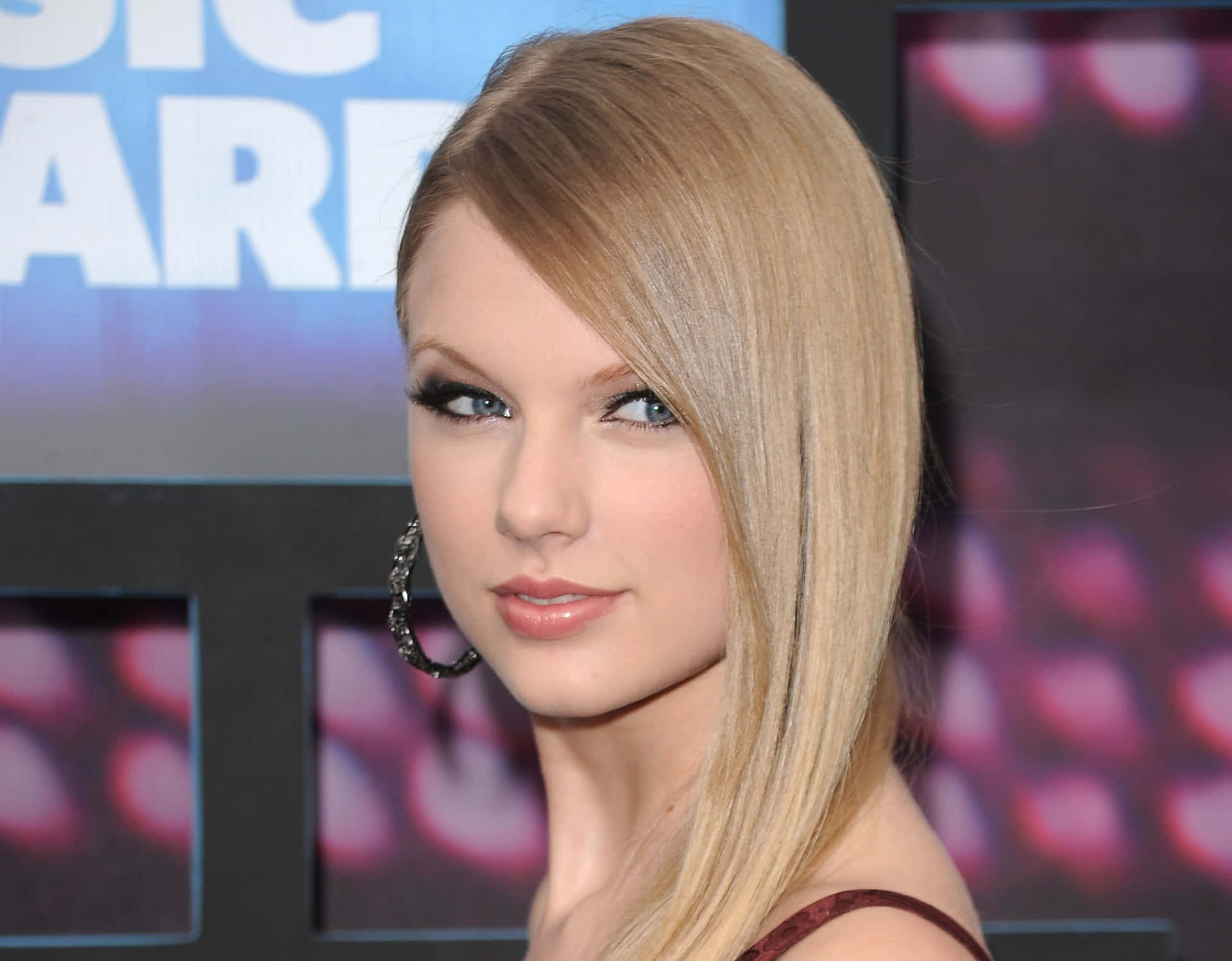 Taylor Swift 在音樂頒獎活動中穿著紅色連衣裙和耳環。
