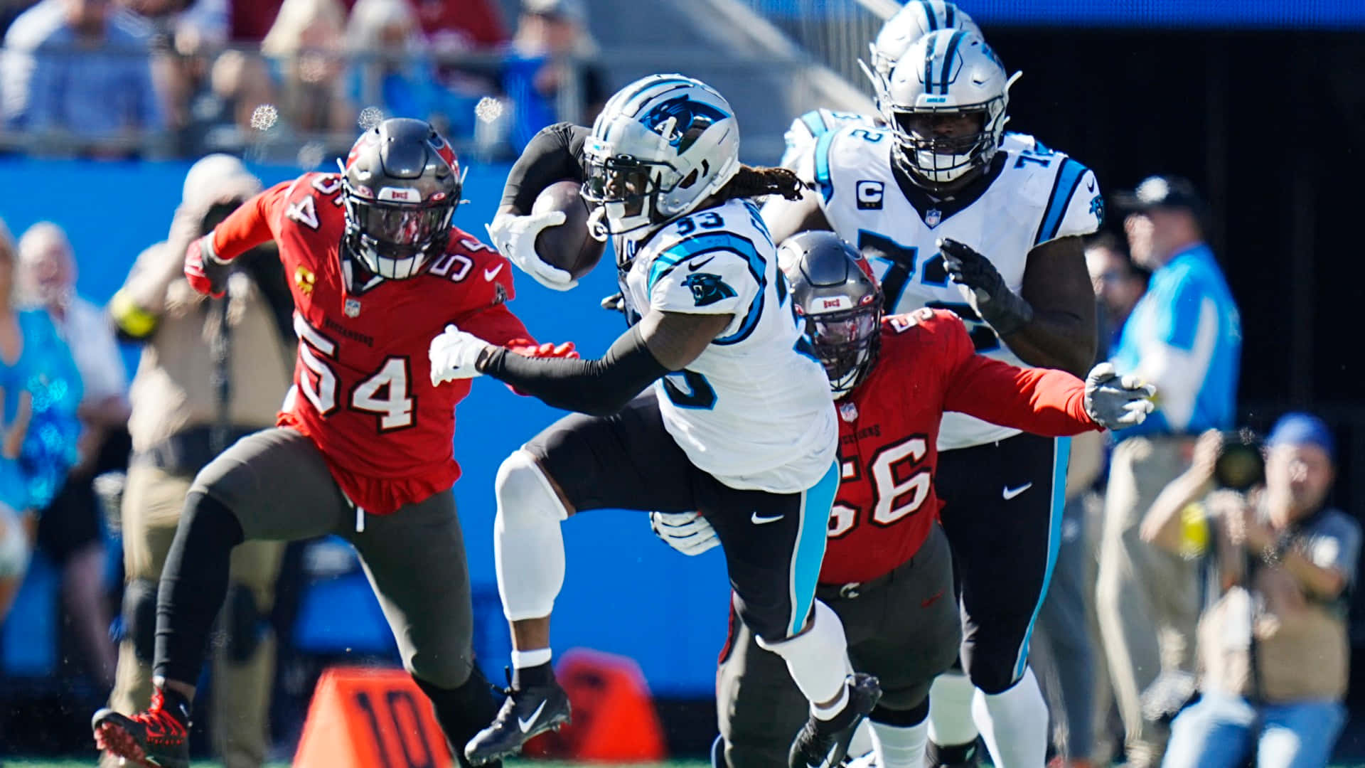 NFL美式足球運動員在日間比賽中進行擒抱和跑動進攻。