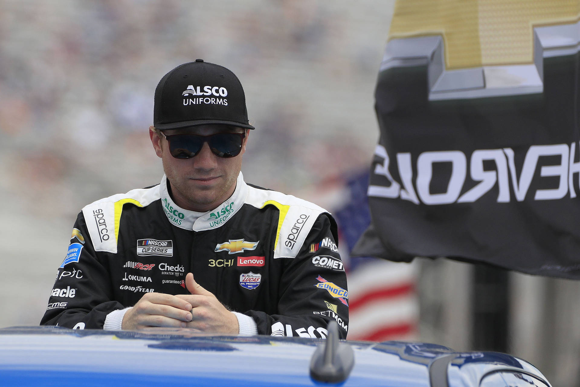 NASCAR車手穿著賽車裝備坐在賽道上的藍色賽車上。