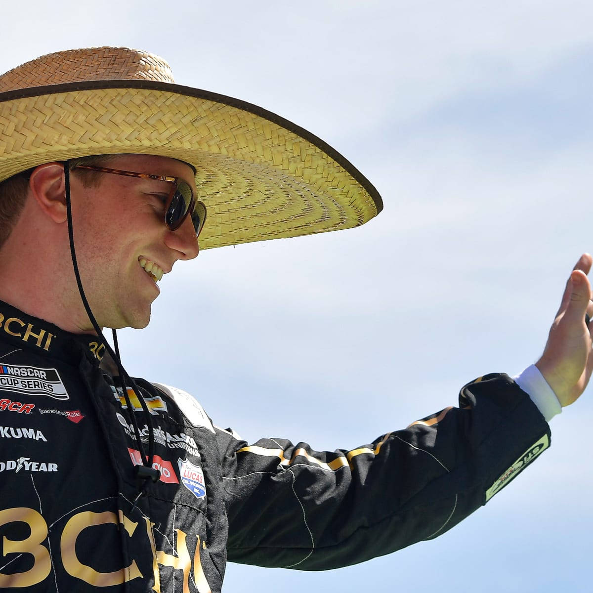 戴草帽和太陽眼鏡的NASCAR車手向人群揮手。