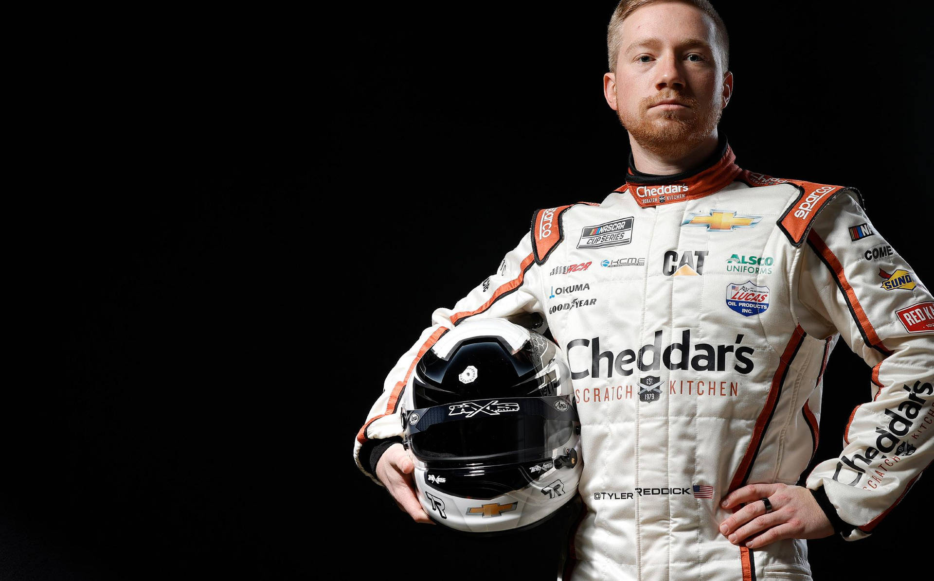 NASCAR車手身穿賽車服在黑色背景下拿著頭盔
