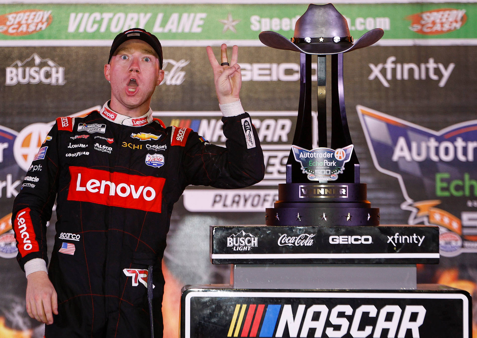 NASCAR車手在帶有牛仔帽的獎盃旁以和平手勢慶祝勝利。