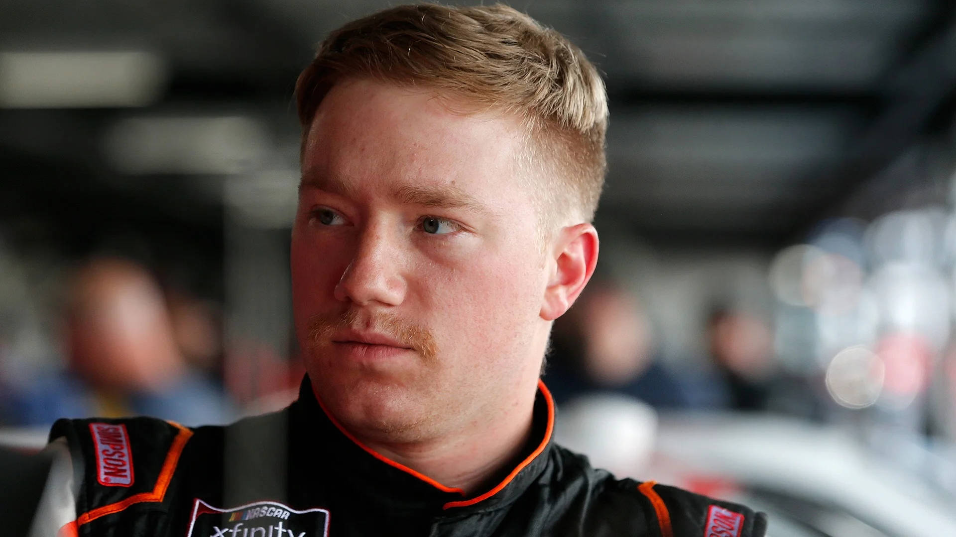 身穿賽車服的NASCAR Xfinity車手在室內專注地凝視。