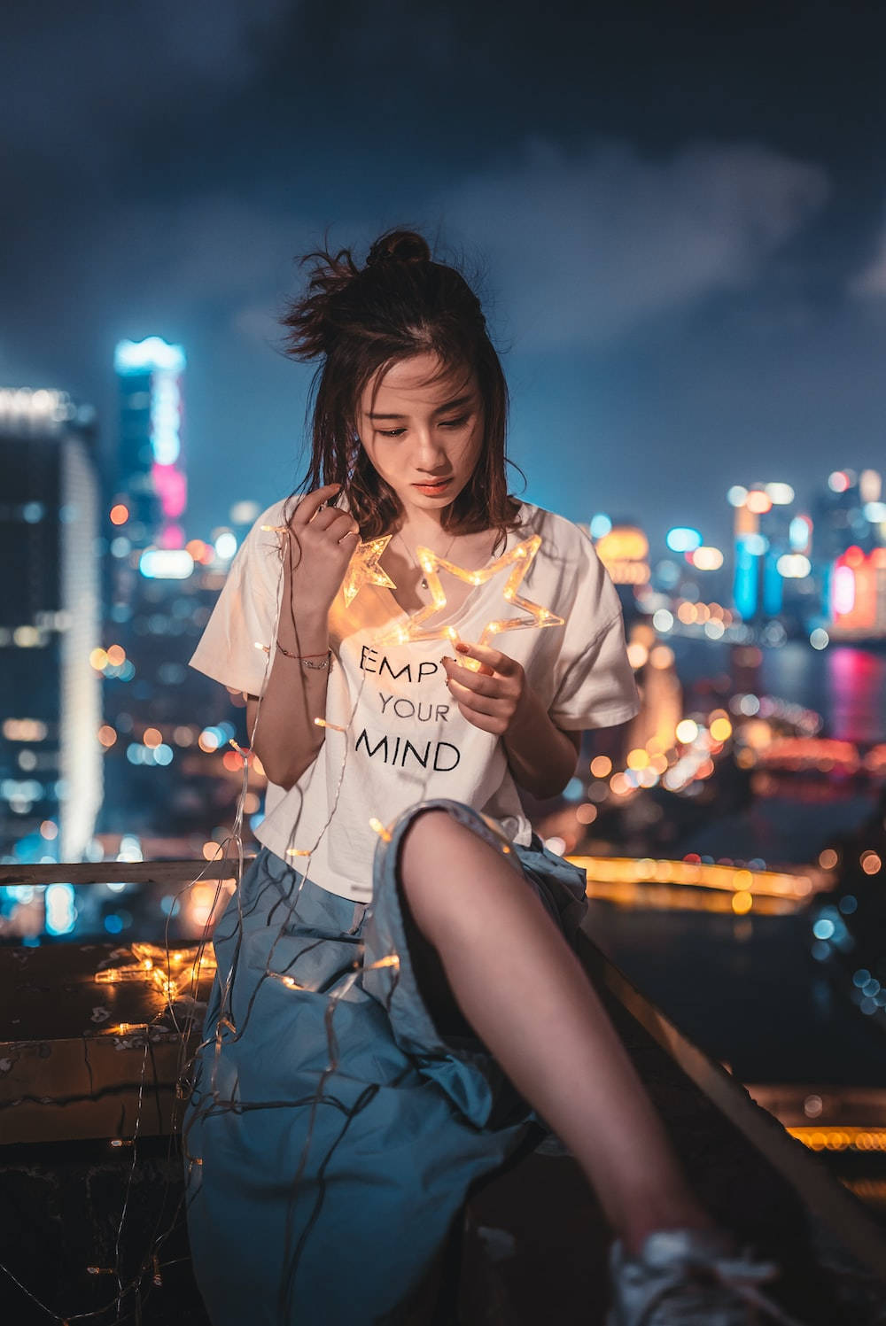 女性夜晚在城市屋頂上手持發光的仙女燈。