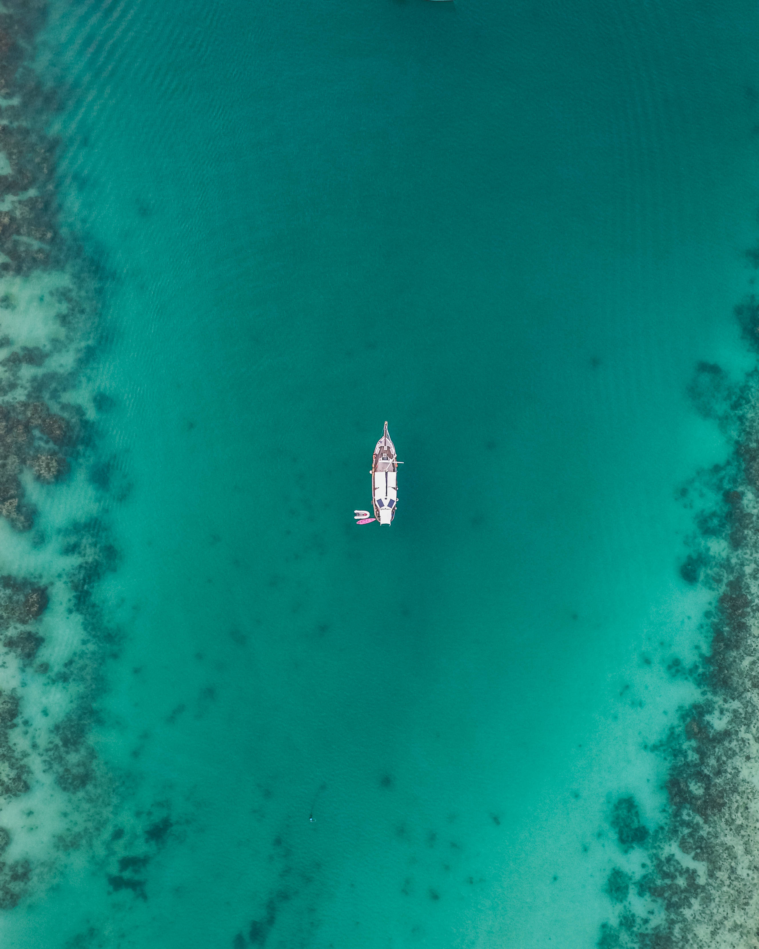 泰國海景空中俯瞰桌面 壁紙 — 俯瞰一名孤獨的槳板運動員在充滿活力的碧綠海水上漂流，周圍環繞著珊瑚礁。