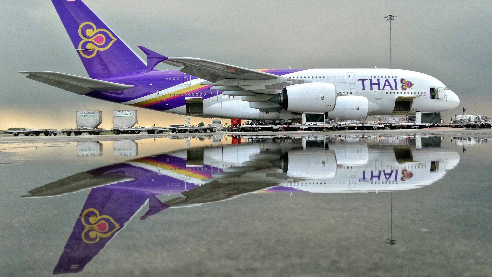 灰色天空下，泰國航空A380飛機倒映在濕滑的機場停機坪上。