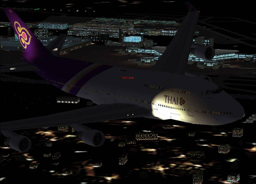 泰國航空747在夜間飛越燈火通明的機場，下方有城市燈光。