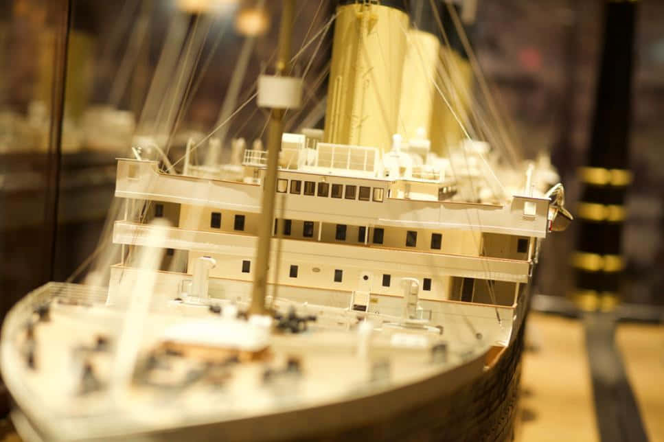 泰坦尼克號博物館船模特寫 壁紙 — 在溫暖的博物館燈光下展示的鐵達尼號詳細模型，背景柔和。