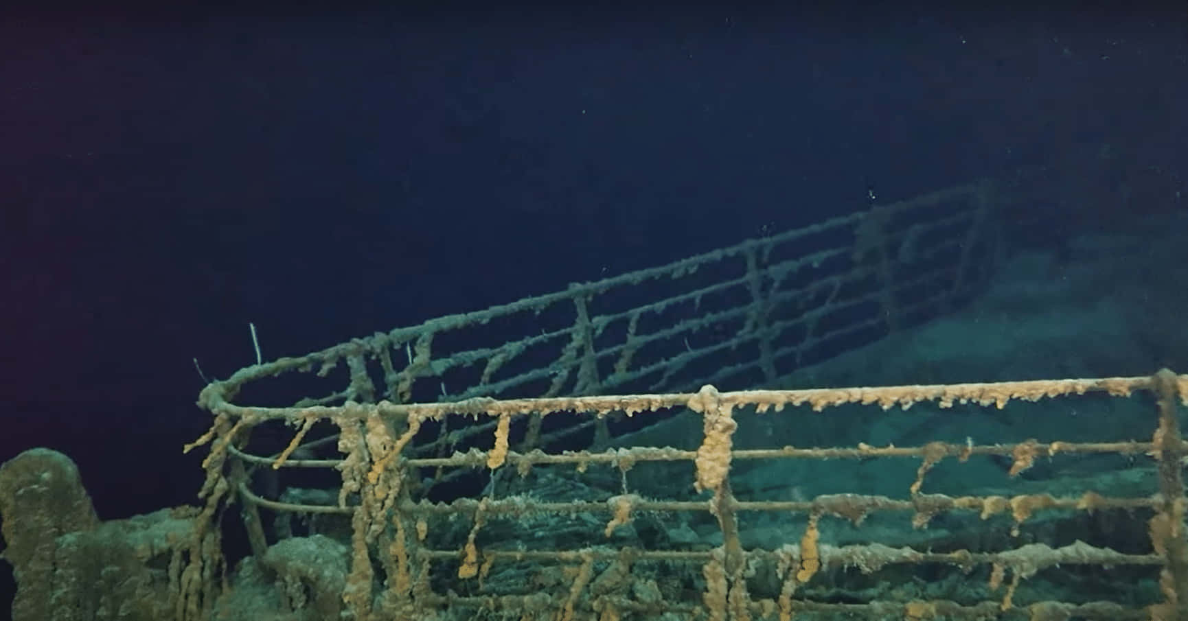 深海黑暗中覆蓋著海洋生物的生鏽沉船欄杆