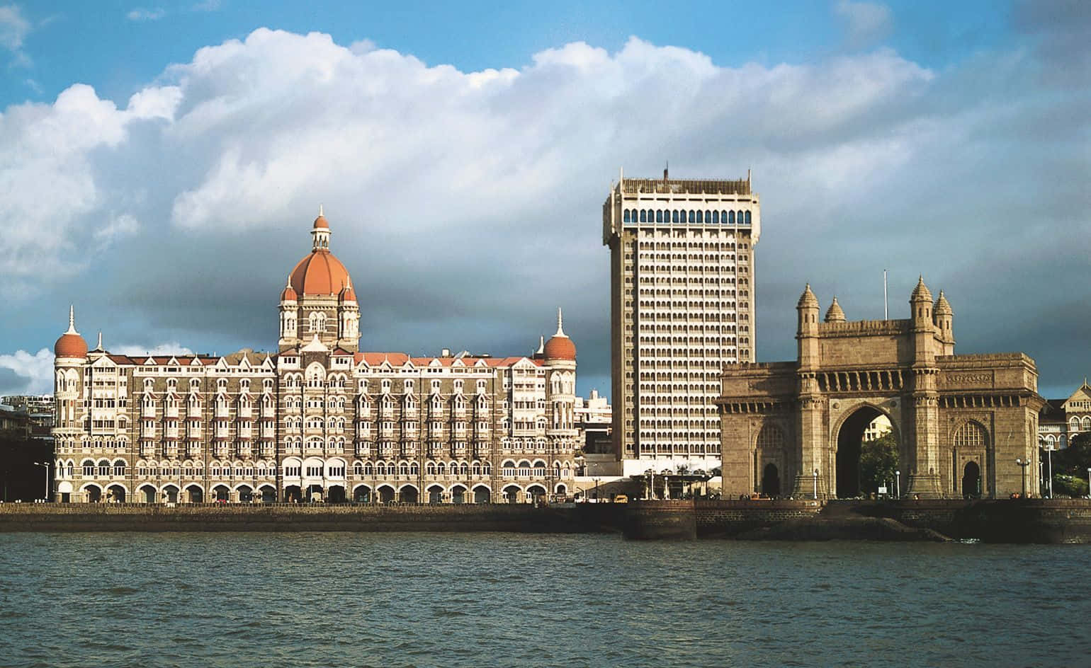 Mumbai 桌布 壁紙 — 泰姬瑪哈皇宮酒店和印度門的宏偉殖民時期建築，在部分多雲的天空下，雄偉地矗立在孟買的海濱。