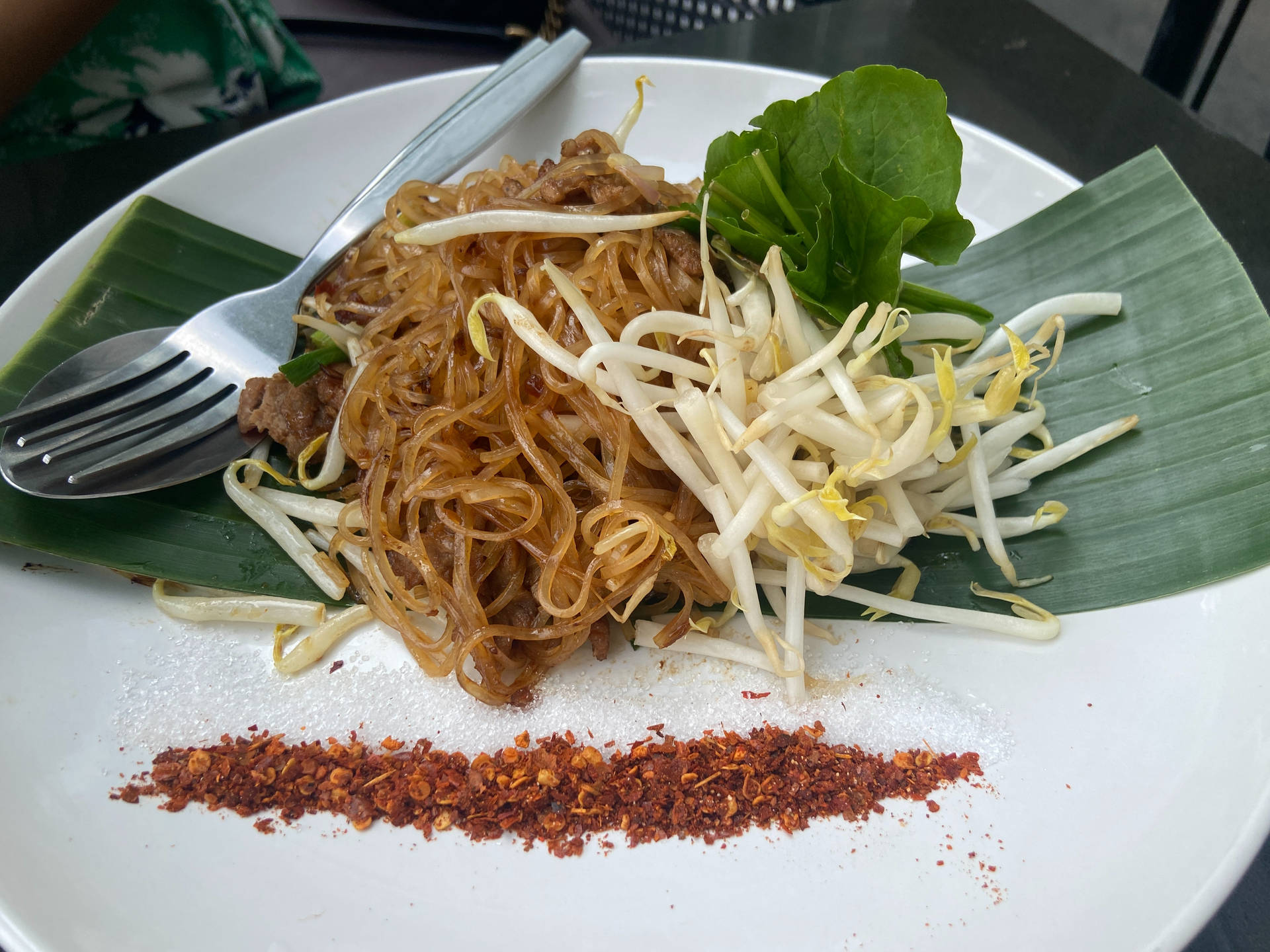 在香蕉葉上，炒米粉配芽菜和辣椒片。