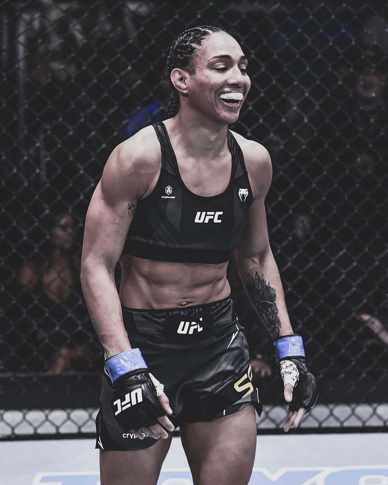 女性MMA拳手在UFC八角籠中以燦爛笑容慶祝勝利。