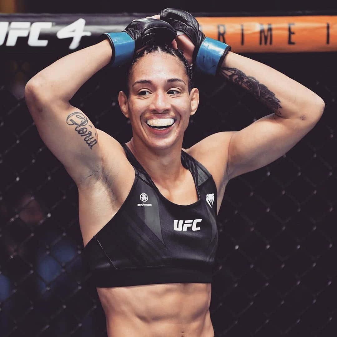女性MMA拳手在八角籠內微笑舉起雙臂。