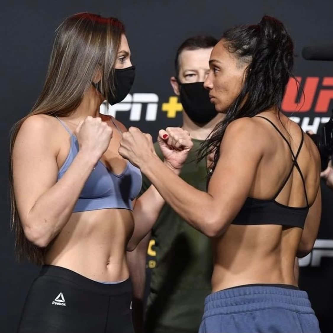 兩名穿著運動服的女性拳手在賽前對峙中鎖定拳頭。