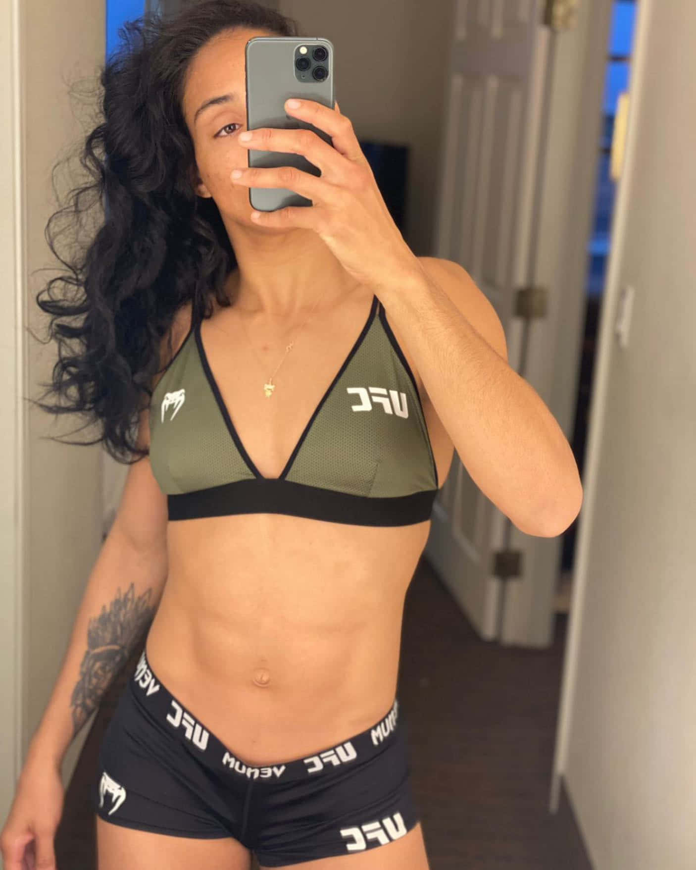 穿著UFC裝備的女性在室內對著鏡子自拍