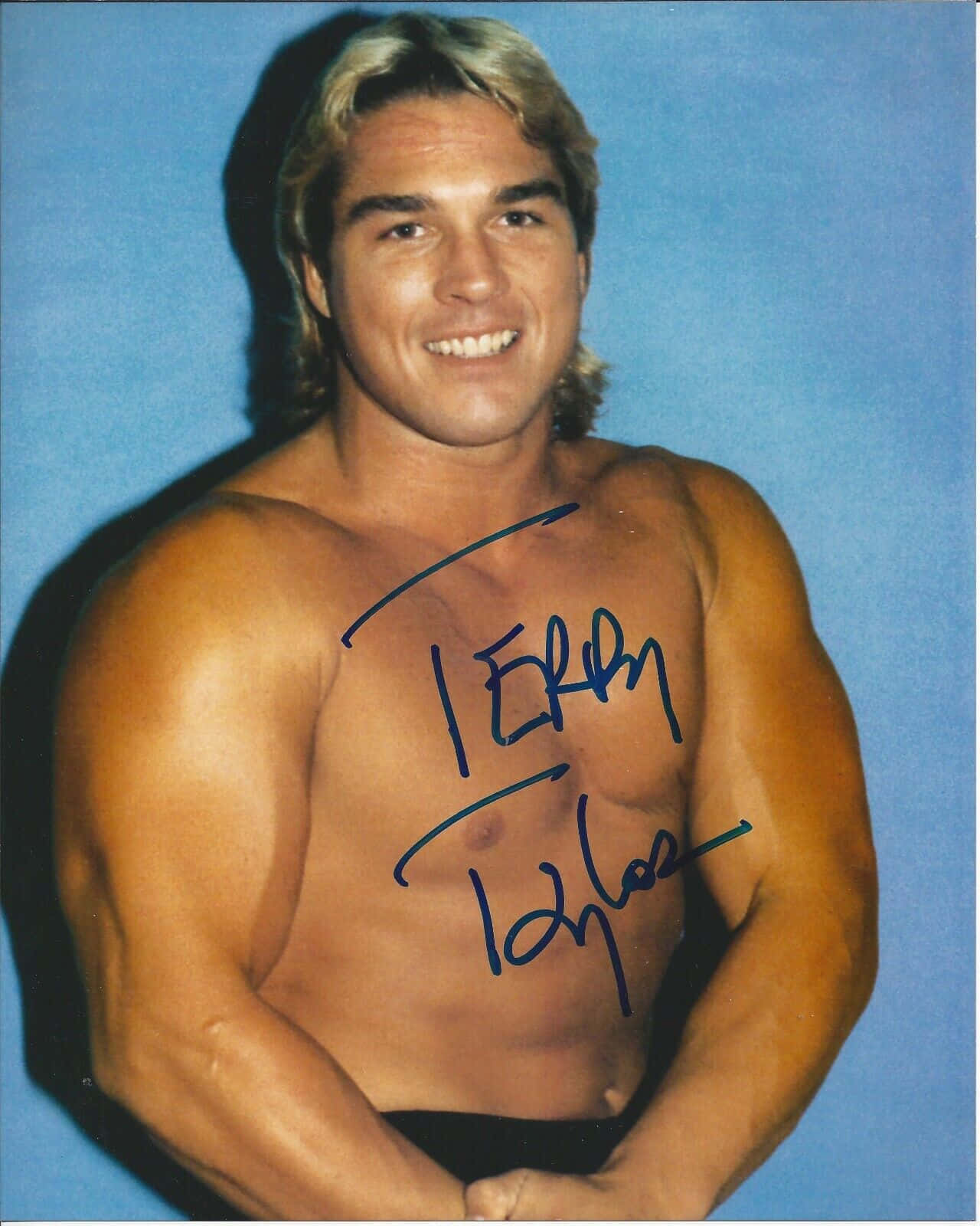 赤膊肌肉摔角手 Terry Taylor 在藍色背景前微笑，胸前有簽名。