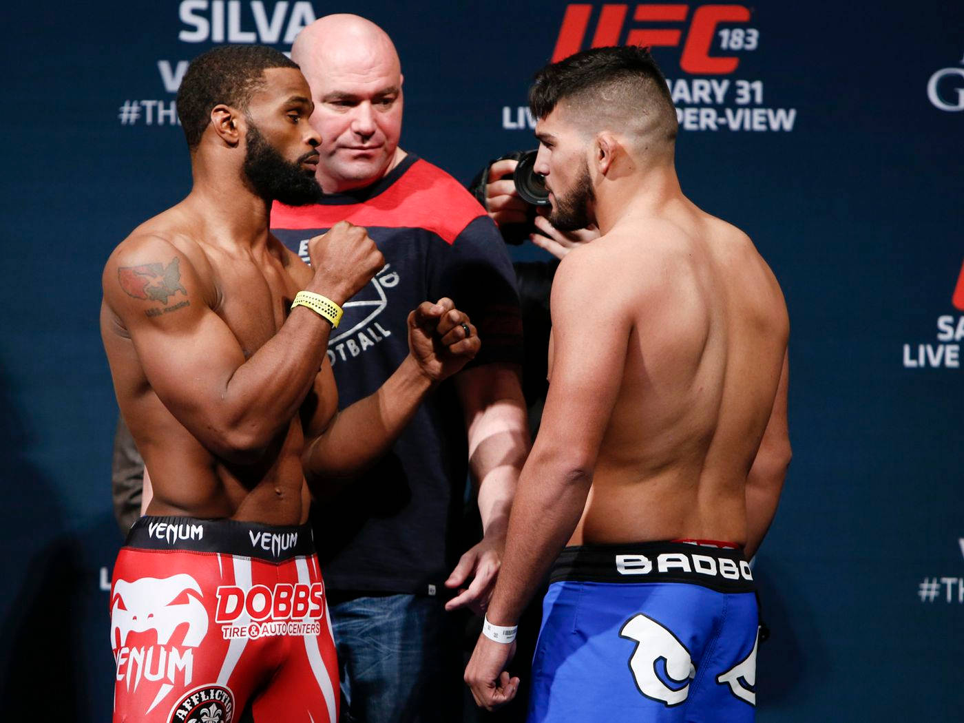 兩名男性MMA拳手穿著紅色和藍色短褲在UFC稱重活動中對峙。