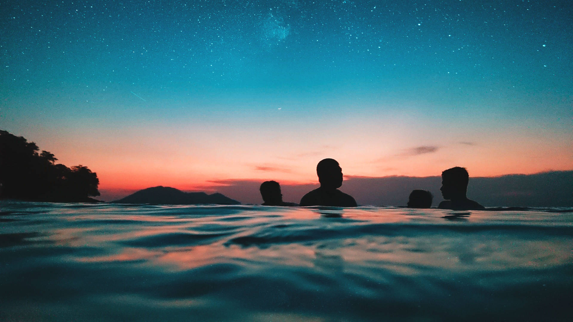 四個人在星空暮色天空下的水中剪影。