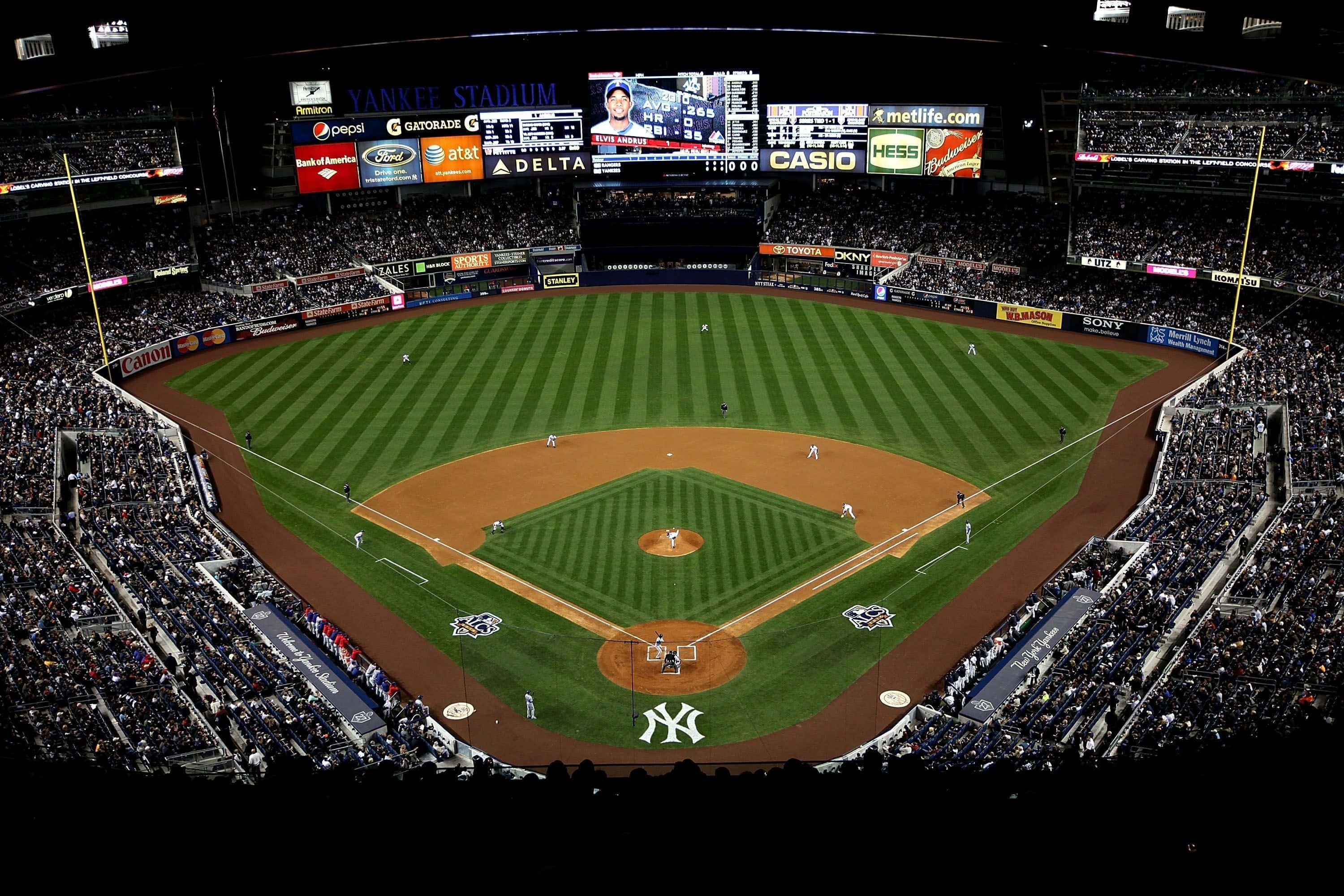 Baseball Stadium 桌布 壁紙 — 洋基球場夜間鳥瞰圖，球場上有球員，看台座無虛席，球場燈光璀璨。