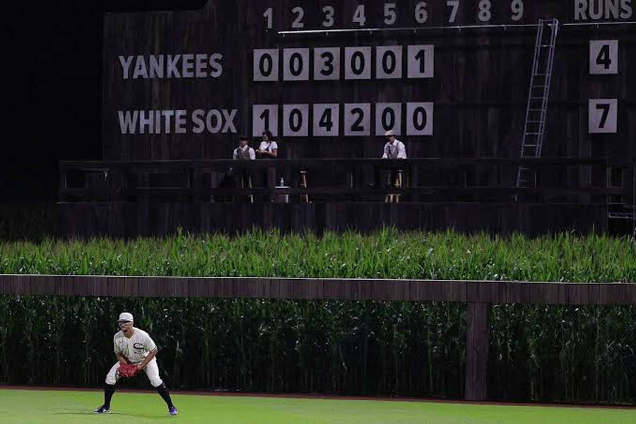 洋基隊對白襪隊 MLB 分數板 壁紙 — 一名身穿白色球衣的棒球手在綠色球場上蹲下，上方有一個大型木製記分牌，顯示洋基隊對白襪隊的比分。
