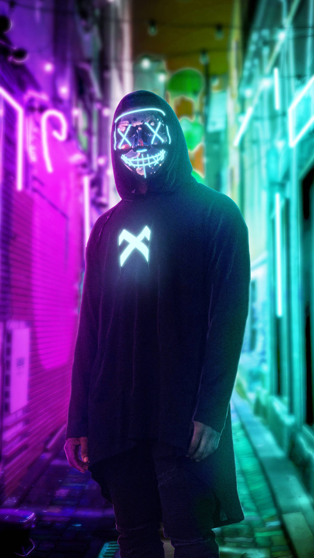 戴著發光面具和連帽衫的人夜晚站在霓虹小巷中。